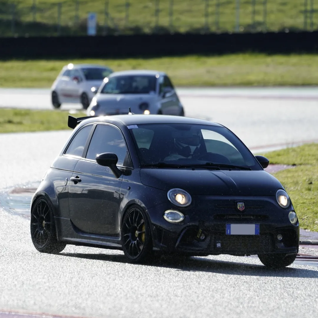 Abarth 500 nera preparata da pista in curva su circuito bagnato